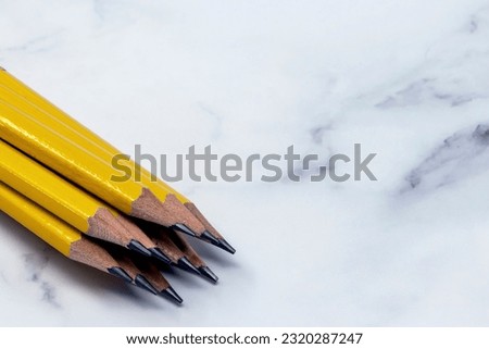 close up image of sharpened pencils points on a white marble background
