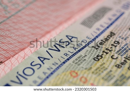 close-up part of page of document, foreign passport for travel with European Ireland visa, tourist visa stamp with hologram with shallow depth of field, passport control at border, travel in Europe