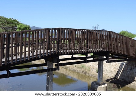 Aceh, Indonesia - June, 2023: A wooden bridge with a dry river due to a long drought. No people.