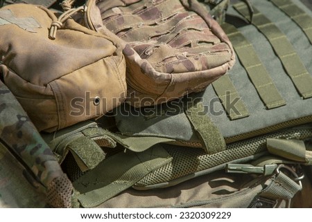 Bag, backpack and body armor of a military man. Old equipment. Outfit. Pixel uniform. Textile green background. A first-aid kit and marching things of a soldier.