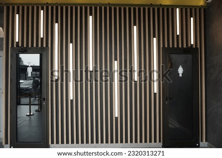 toilets with dark door and wall themes decorated with vertical neon lights