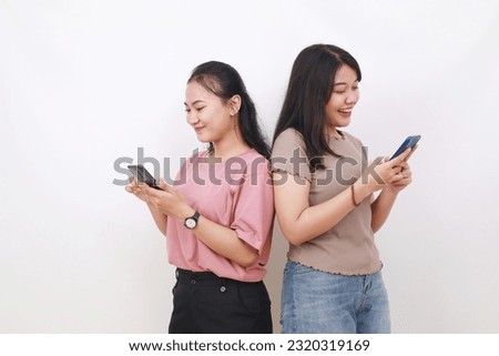 Two asian women hold in hand use cell phone browsing internet chatting online isolated on white