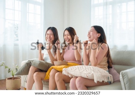 Portrait of Happy Smiling Three young Asian Women cheering watching game and enjoying on Television on sofa. Excited Pretty Girl models having Fun and shouting on couch. Group of female friends