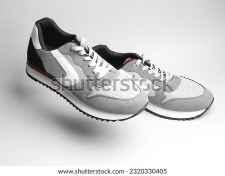 Gray sports sneakers floating on a gray background with shadow Royalty-Free Stock Photo #2320330405