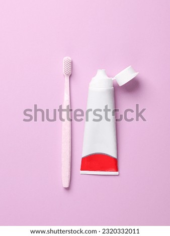 Toothbrush and toothpaste tube on purple pastel background. Top view