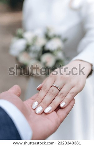 bride hand lying on groom hand, bride in white dress holding wedding bouquet, love and family concept, vertical photo
