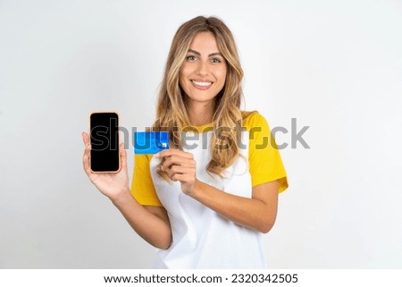 Photo of adorable Young beautiful woman wearing football T-shirt holding credit card and Smartphone. Reserved for online purchases