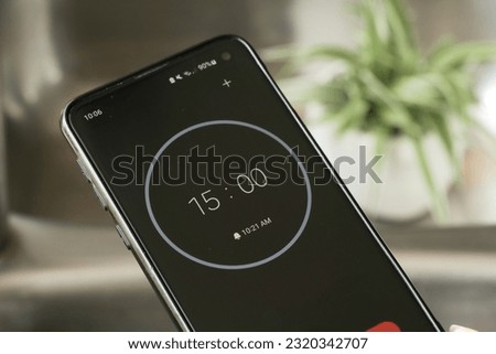 A phone with a black and white 15-minute timer to study with the pomodoro method on a blurry background Royalty-Free Stock Photo #2320342707