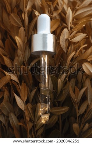 Gold particles glittering serum bottle with dropper. Concept natural organic cosmetic. Collagen Oil serum dropper on beautiful vegetable brown background.
