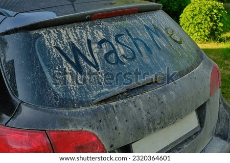 On the glass of a very dirty and dusty car there is a funny inscription "WASH ME", at the bottom you can see an empty license plate frame without inscriptions. Humor, car wash, car care.