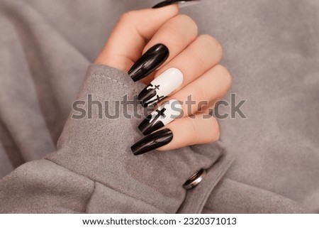 Halloween nail design black white color with cross. Female hand with autumn manicure, top view. Halloween concept
