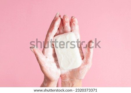 Washing of hands with soap. Cleaning hands. Closeup on woman hands with soap bar on pastel pink background. Royalty-Free Stock Photo #2320373371