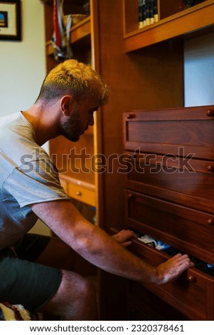 Man picking up clothes at home in drawers Royalty-Free Stock Photo #2320378461