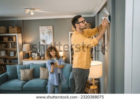 Couple adult caucasian man and woman at home connecting setup and install cctv security video surveillance camera monitoring system Royalty-Free Stock Photo #2320388075