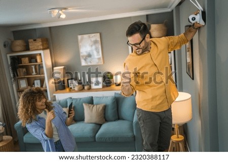 Couple adult caucasian man and woman at home connecting setup and install cctv security video surveillance camera monitoring system Royalty-Free Stock Photo #2320388117