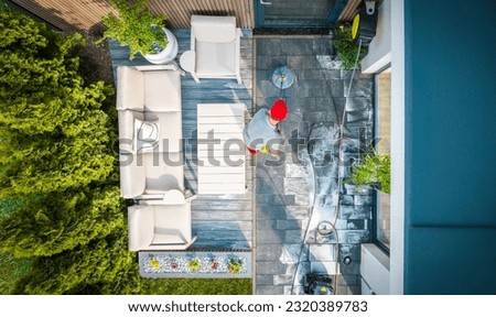 Top View of Caucasian Home Owner Washing the Walkway at His Small Backyard Terrace with Power Surface Cleaner Tool.
