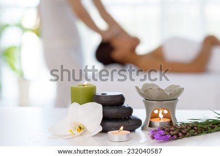 Spa concept: zen stones, candles and flowers on the background of woman receiving treatment Royalty-Free Stock Photo #232040587
