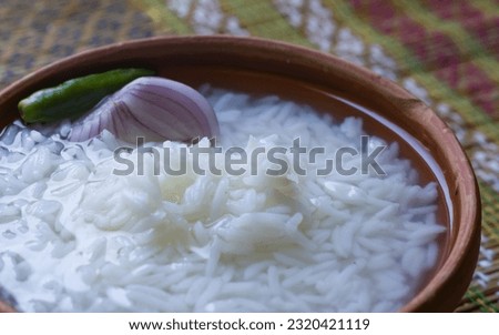 Panta bhat or pakhala or fermented rice soup with water is served in clay bowl with raw onion and green chilli. It is traditional staple cool food of Bengal and odisha during summer season of boisakh. Royalty-Free Stock Photo #2320421119
