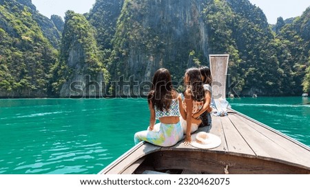 Group of Young Asian woman friends sitting on wooden boat passing tropical island beach in sunny day. Attractive girl enjoy outdoor lifestyle travel ocean on summer holiday vacation at Krabi, Thailand Royalty-Free Stock Photo #2320462075