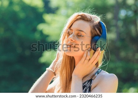 Relaxed woman listening to music and breathing fresh air in a forest or park.