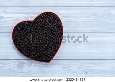 Coffee beans in a heart shaped box  with white wooden textured table, Healthy coffee concept image