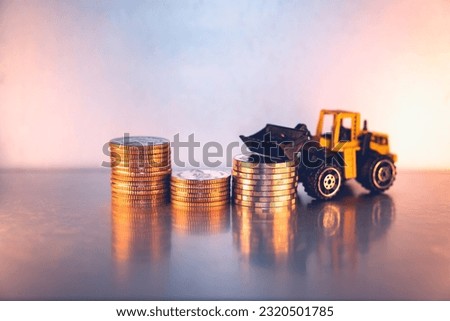 Closeup stack coins with forklift vehicle using as business and logistics industry concept