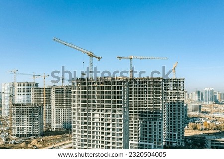 construction site with cranes and apartment buildings under construction against blue sky. housing construction concept. aerial photo.