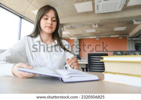 A cute schoolgirl is sitting at a desk at school. The concept of schooling