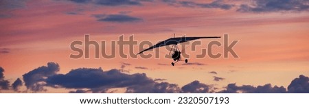 Hang glider on a motor on a summer evening against the backdrop of a sunset sky. Extreme sport. Banner, blank for an advertising layout with a place for writing Royalty-Free Stock Photo #2320507193