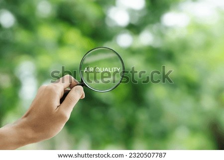 hand holding a magnifying glass to check the  good air quality and clean outdoor air quality safe from pollution dust PM 2.5 Royalty-Free Stock Photo #2320507787