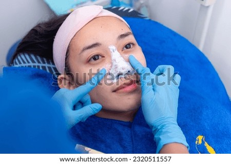 Applying topical anesthesia to the nose to numb the skin. Preoperative procedure for an open rhinoplasty procedure.