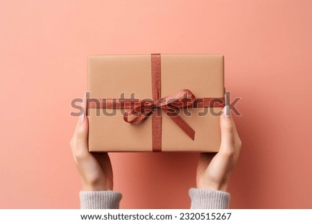 Female hands holding wrapped brown package gift box made of natural corrugated cardboard. simple and clean solid color background. packaging, shopping, delivery concept. 