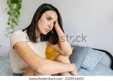 Portrait of upset young adult woman feeling sad sitting on bed feeling sad at home Royalty-Free Stock Photo #2320516655