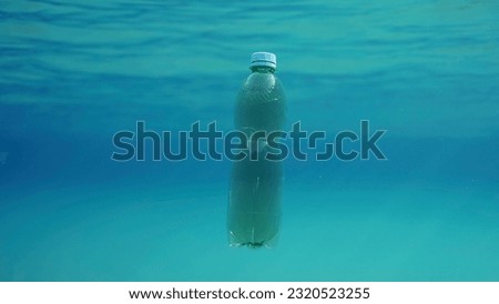 Green plastic bottle drifting under surface of blue water. Plastic pollution of Ocean, Discarded plastic bottle floats underwater in sunlight, Red sea, Egypt Royalty-Free Stock Photo #2320523255
