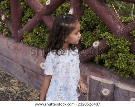 Little girl wearing white and black dresses in park .Blur background of clear focus portrait photo.different face style with awesome pose.Street poster and wallpaper images using for home decor.