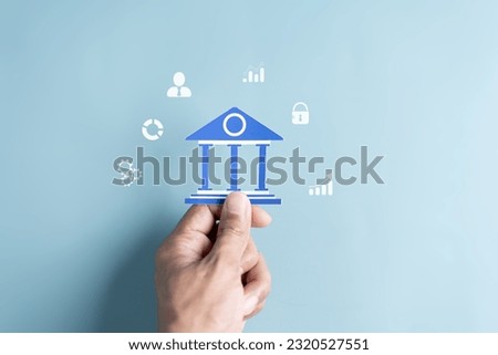Hand Holding Bank Government building paper cut out, Transaction and banking current financial concept. Royalty-Free Stock Photo #2320527551
