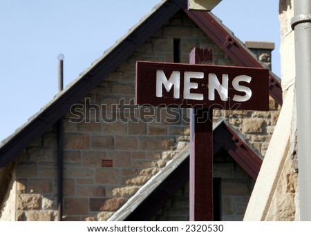 Public Mens Restroom / Toilet Sign On Wood In Front Of A Brick House