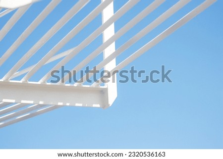 white painted iron girders and bracing bars against a clear blue sky