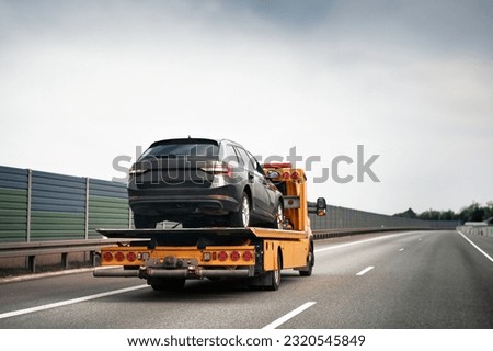 Tow truck with broken car on country road. Tow truck transporting car on the highway. Car service transportation concept. Royalty-Free Stock Photo #2320545849