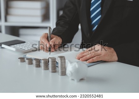 Person with pile of coins and piggy bank, money saving concept for future use and financial stability, salary management, personal finance, investment savings. Royalty-Free Stock Photo #2320552481