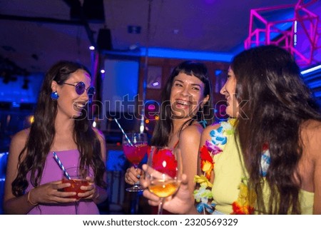 Fun of female friends in a nightclub dancing with the glasses at a summer night party in a pub
