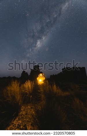 Night time long exposure landscape photography. A man standing in a high place looking up in wonder to the Milky Way galaxy, photo composite.
