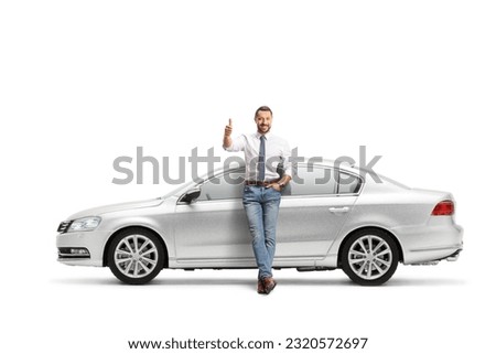 Full length portrait of a man leaning on a silver car and gesturing thumbs up isolated on white background