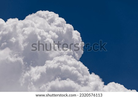 High Altitude Cumulonimbus Clouds: Stormy Skies and Clear Blue Background. Puffy White Clouds, Monsoon Clouds Formation. Stunning Weather with Deep Blue Sky and Huge Clouds. Royalty-Free Stock Photo #2320576113