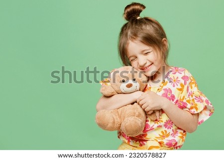 Little happy child kid girl 6-7 year old wear casual clothes have fun hold hug teddy bear plush toy isolated on plain pastel green background studio portrait Mother's Day love family lifestyle concept Royalty-Free Stock Photo #2320578827