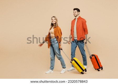 Traveler fun couple two friend family man woman wear casual clothes hold suitcase go isolated on plain beige background Tourist travel abroad in free spare time getaway Air flight trip journey concept