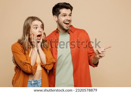 Young shocked surprised couple two friends family man woman wears casual clothes look aside point index finger on area together isolated on pastel plain light beige color background studio portrait Royalty-Free Stock Photo #2320578879