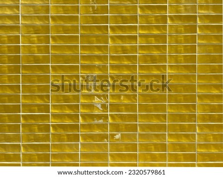 Various shades of vibrant vivid glazed golden yellow mosaic ceramic tiles on wall textured background