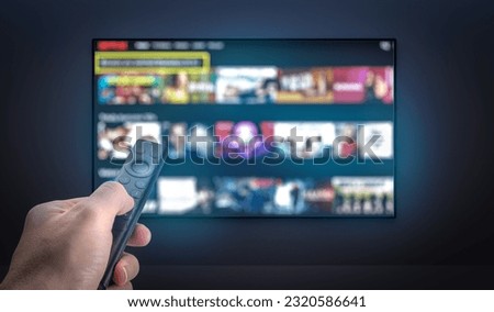 Streaming service. TV screen with lot of pictures and hand holding TV remote control. Multimedia Television video streaming, Media TV on demand. Subscription Streaming video