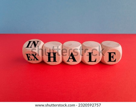 Inhale, Exhale concept. Turned a dice and changes the word INHALE to EXHALE. Beautiful blue background, red table, copy space. Business and INHALE or EXHALE concept.